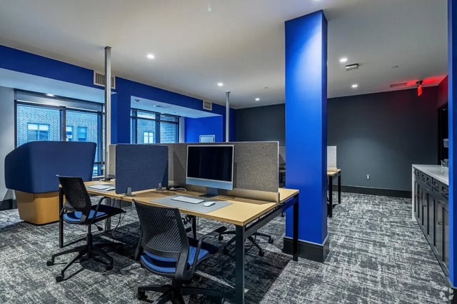 Desks computers chairs and blue partition study area at Vic Village South in Ann Arbor Student Accommodation