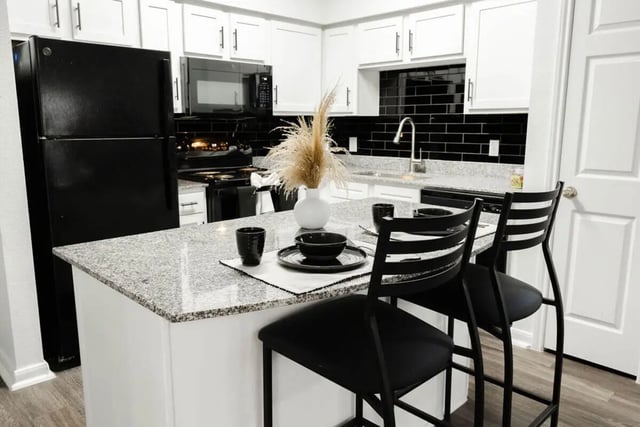 Black refrigerator counter with chairs kitchen at Villagio Apartments in San Marcos Student Accommodation