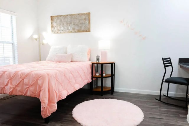 Pink duvet bed bedside table black chair bedroom at Villagio Apartments in San Marcos Student Accommodation