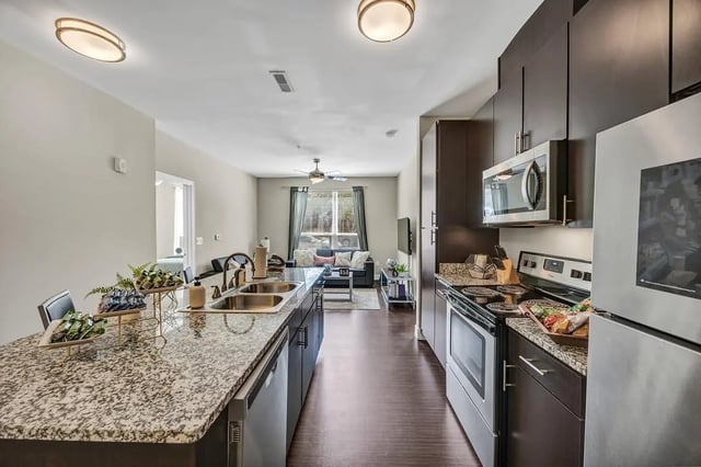 Kitchen with granite island stainless steel appliances living area living room at Park Place Waco in Waco Student Accommodation