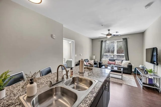 Granite kitchen island double sink black chairs living room at Park Place Waco in Waco Student Accommodation