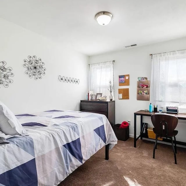 Bed dresser desk chair and window bedroom at The Hills Northview Apartments in Harrisonburg Student Accommodation