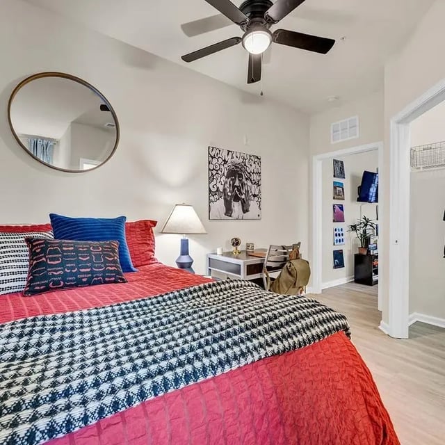 Red bed blue pillows art desk closet bedroom at The Luxe on West Call in Tallahassee Student Accommodation
