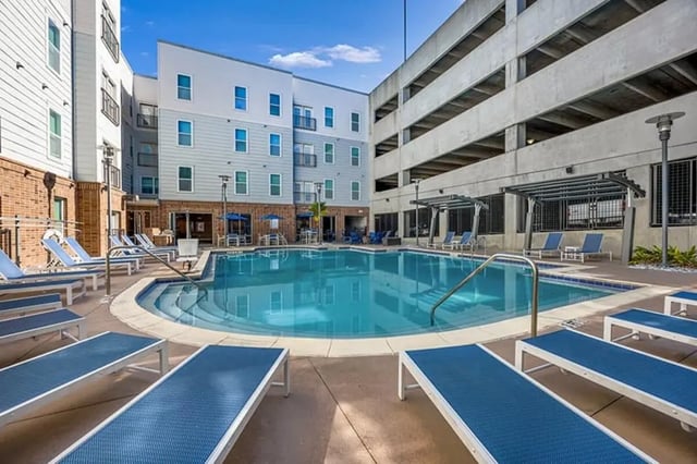 Blue lounge chairs surround bright pool area exterior at The Luxe on West Call in Tallahassee Student Accommodation