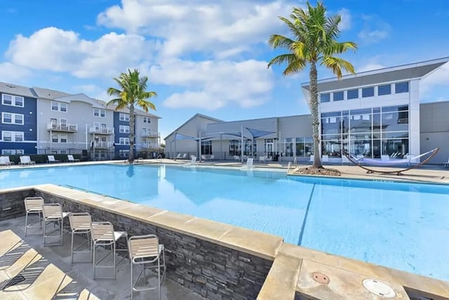 Pool with chairs and palm trees exterior at The Avenue at San Marcos in San Marcos Student Accommodation
