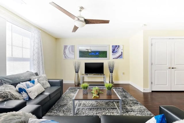 Black couch with pillows ceiling fan television living room at The Avenue at San Marcos in San Marcos Student Accommodation