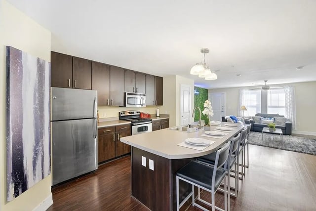 Stainless steel refrigerator dark cabinets island seating living room kitchen at The Avenue at San Marcos in San Marcos Student Accommodation