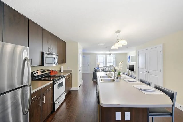 Stainless refrigerator dark cabinets oven island kitchen and living room. at The Avenue at San Marcos in San Marcos Student Accommodation