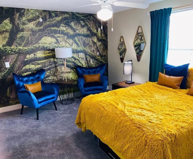 Two blue chairs wall mural bed and pillows bedroom at The Avenue at San Marcos in San Marcos Student Accommodation