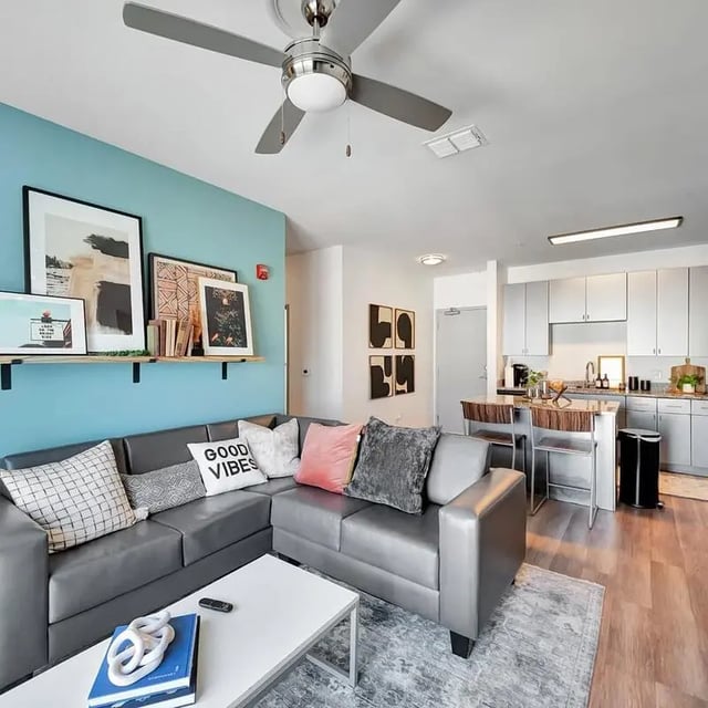Sectional couch white coffee table kitchen living room at The Rowe Apartments in Tallahassee Student Accommodation