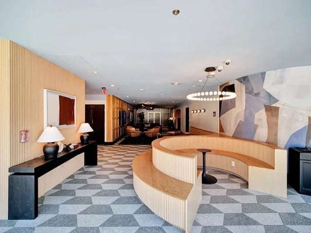 Curved wooden bench with table and abstract wall art lounge area at The Rowe Apartments in Tallahassee Student Accommodation