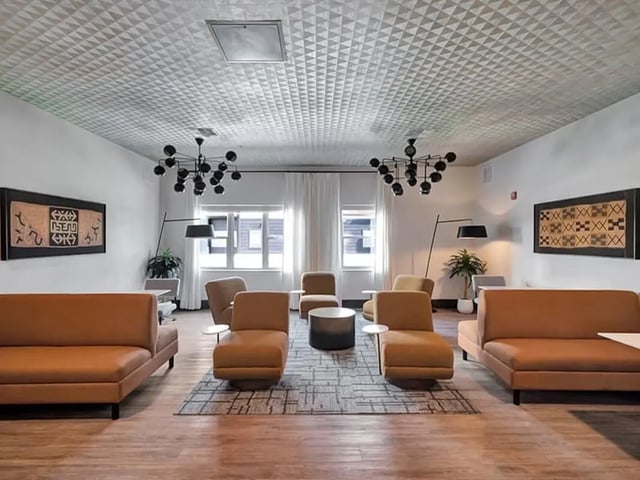 Sofa chairs table artwork and chandelier living room at The Rowe Apartments in Tallahassee Student Accommodation