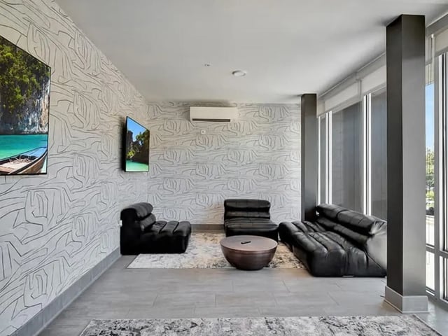 Black leather sofas and chairs coffee table living room at The Rowe Apartments in Tallahassee Student Accommodation