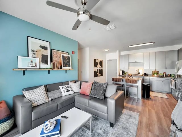 Gray sectional sofa framed art kitchen living room at The Rowe Apartments in Tallahassee Student Accommodation