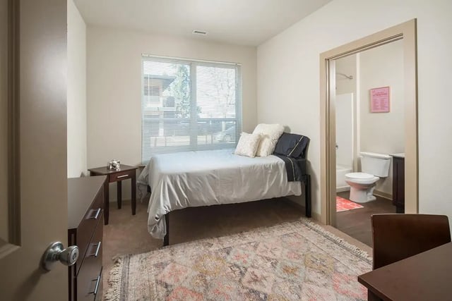 Bed dresser rug and open bathroom Bedroom at The Hayward Student Living in Eugene Student Accommodation