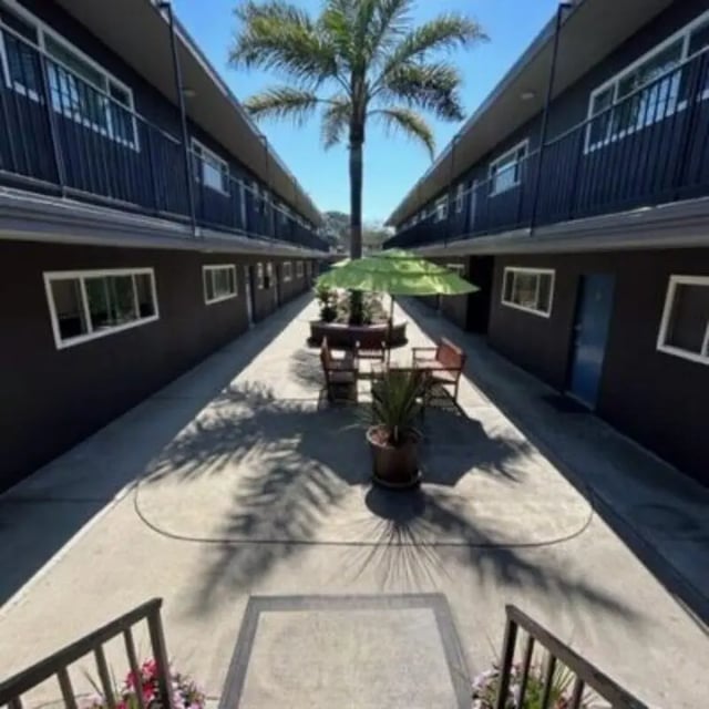 Courtyard with tables chairs umbrella and palm tree exterior at Capri at Isla Vista Apartments in Isla Vista Student Accommodation