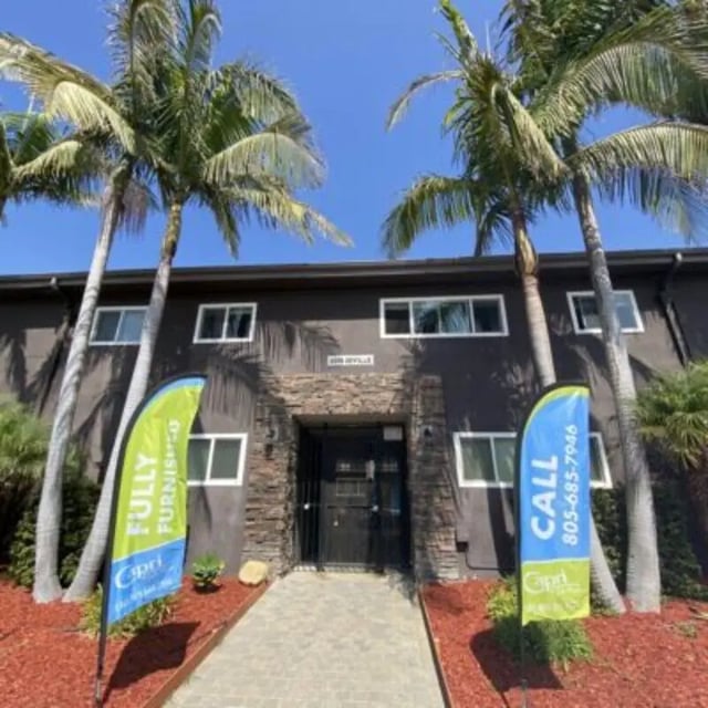 Palm trees on building exterior with advertising flags exterior at Capri at Isla Vista Apartments in Isla Vista Student Accommodation