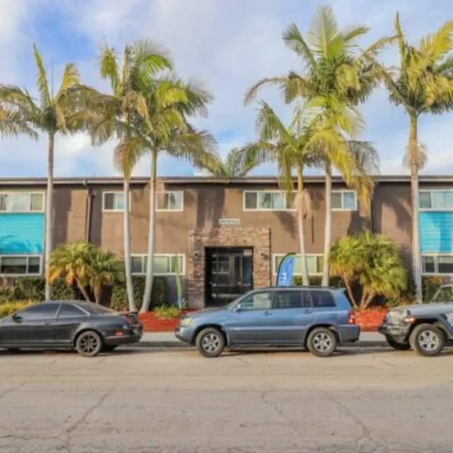 Apartment building with cars and palm trees exterior at Capri at Isla Vista Apartments in Isla Vista Student Accommodation
