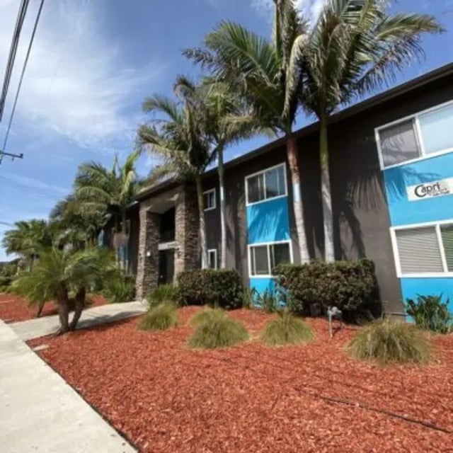 Dark building blue accents palm trees exterior at Capri at Isla Vista Apartments in Isla Vista Student Accommodation