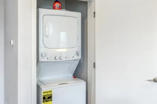 White stacked washer dryer with detergent bottle laundry room at 1301 Hillsborough Apartments in Raleigh Student Accommodation