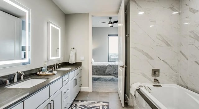 Double sinks illuminated mirrors and a tub bathroom at 1301 Hillsborough Apartments in Raleigh Student Accommodation