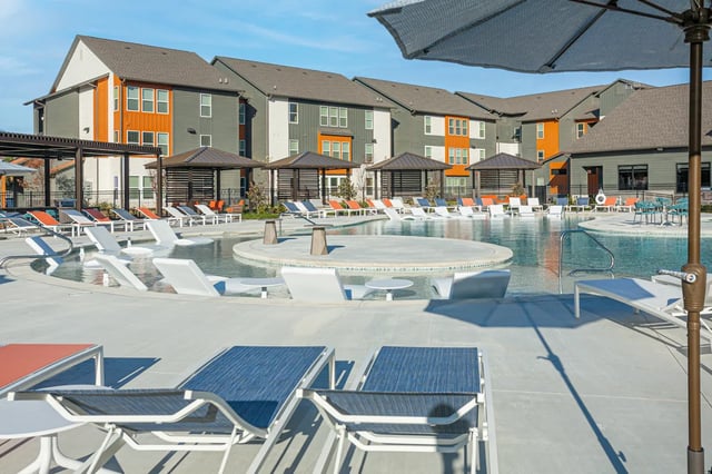 Loungers umbrellas and pool with apartment buildings exterior at Aspen Heights Fayetteville in Fayetteville Student Accommodation