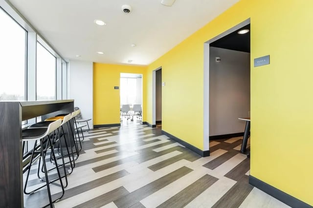 Bar stools at counter with yellow walls common area at Aspen Heights Towson in Towson Student Accommodation