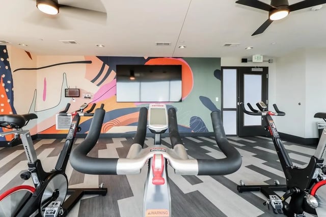 Stationary bikes and TV on colorful wall Gym at Aspen Heights Towson in Towson Student Accommodation