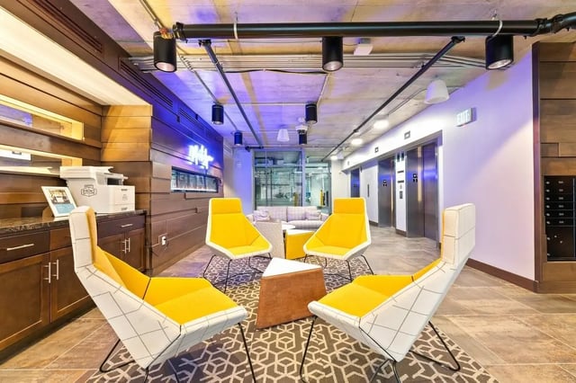 Yellow chairs and geometric rug in lobby area at Aspen Heights Towson in Towson Student Accommodation