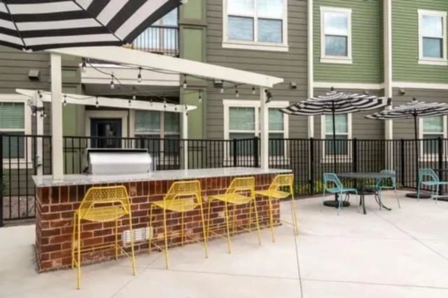 Outdoor bar with yellow stools and grill area exterior at 14 SixtyFive in Kennesaw Student Accommodation