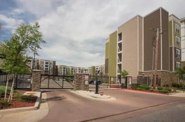 Apartment complex gate with stone pillars and trees exterior at Aspen Springfield in Springfield Student Accommodation