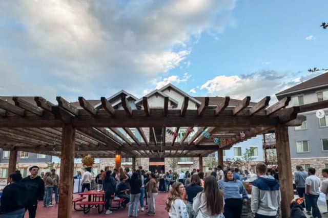People gathered outdoors under a wooden pergola exterior at Alpine Village in Provo Student Accommodation