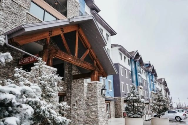 Entrance with stone facade and snow covered trees exterior at Alpine Village in Provo Student Accommodation