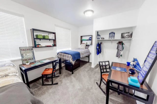 Two beds desks shelves and hanging clothes bedroom at Alpine Village in Provo Student Accommodation