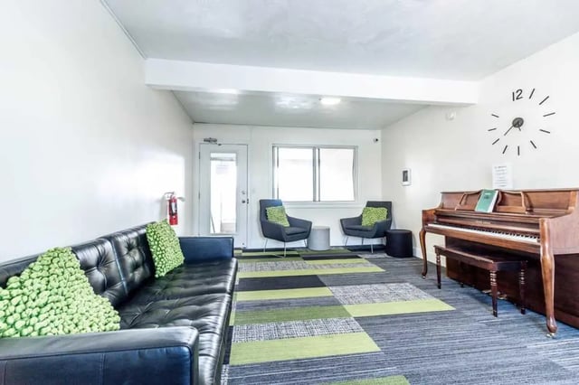 Black couch piano two chairs clock living room at Birch Plaza and Birchwood Apartments in Rexburg Student Accommodation
