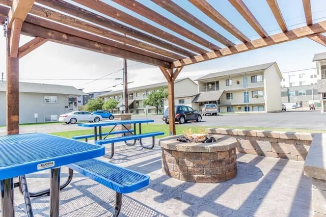Picnic tables fire pit under pergola exterior at Birch Plaza and Birchwood Apartments in Rexburg Student Accommodation