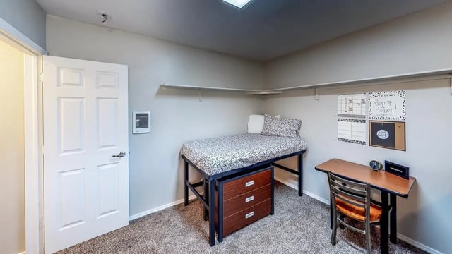 Bed desk and door in student dorm room at Birch Plaza and Birchwood Apartments in Rexburg Student Accommodation