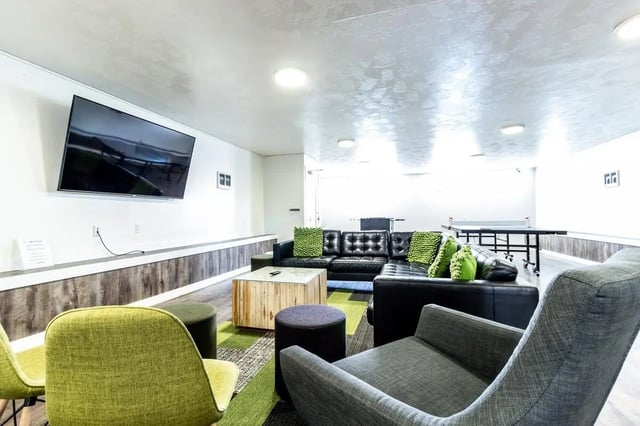 Black leather sofa green pillows ping pong table living room at Birch Plaza and Birchwood Apartments in Rexburg Student Accommodation