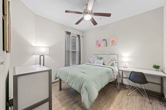 Bed ceiling fan desk chair bedside table bedroom at Altitude Apartments in Houston Student Accommodation