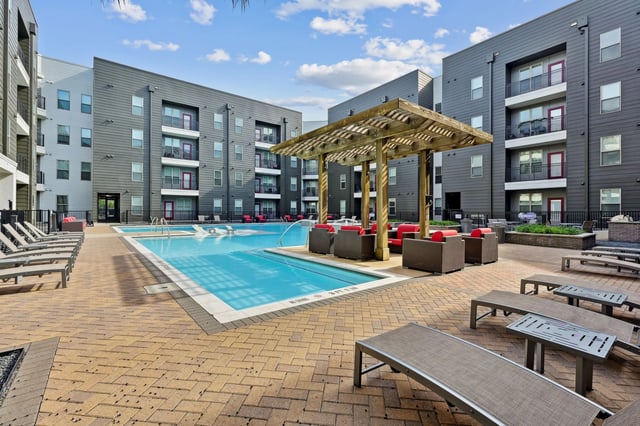 Apartment buildings surrounding a pool and seating area. Exterior at Altitude Apartments in Houston Student Accommodation