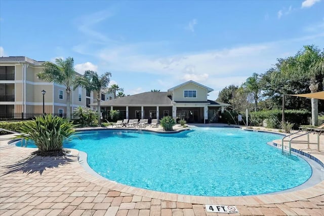 Large pool with lounge chairs and palm trees exterior at Eagle Landing in Daytona Beach Student Accommodation