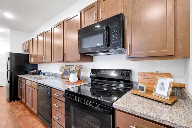 Modern kitchen with black appliances and wooden cabinets Kitchen at Eagle Landing in Daytona Beach Student Accommodation