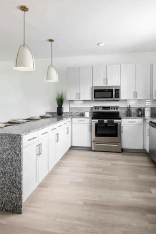White cabinets stainless steel appliances granite island kitchen at Prospect Row in Tallahassee Student Accommodation