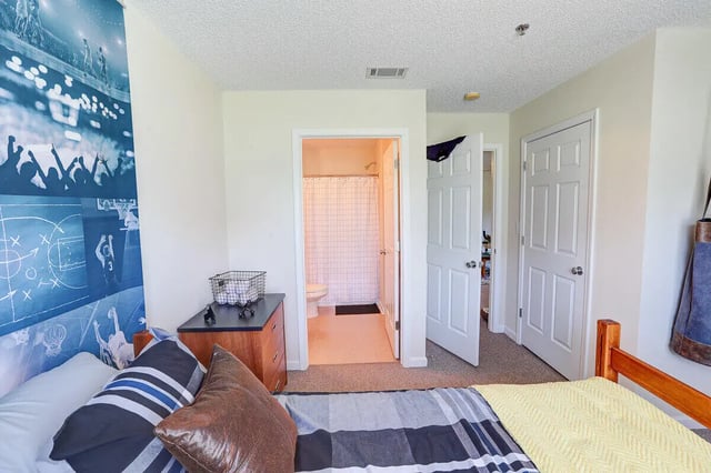 Bed with pillows dresser basket and bathroom Bedroom at Eagles Landing Apartments in Cookeville Student Accommodation