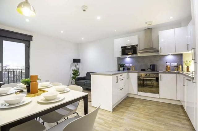 Dining table place settings sofa kitchen with microwave oven at The Bridge Phase II in Newcastle Upon Tyne Student Accommodation