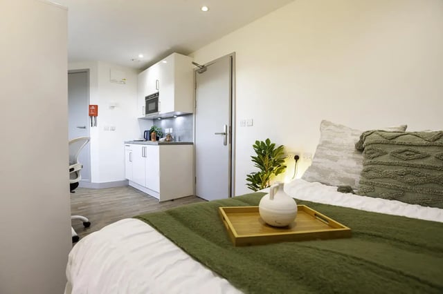 Bed with green throw kitchen area study room at The Bridge Phase II in Newcastle Upon Tyne Student Accommodation