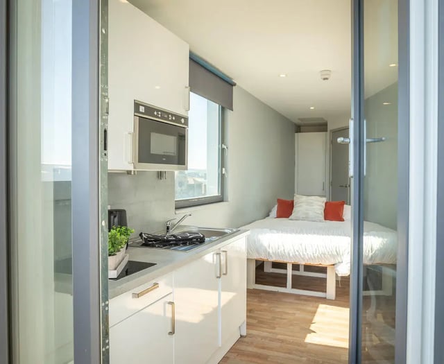 Kitchenette and bed with orange pillows studio apartment at The Bridge Phase II in Newcastle Upon Tyne Student Accommodation