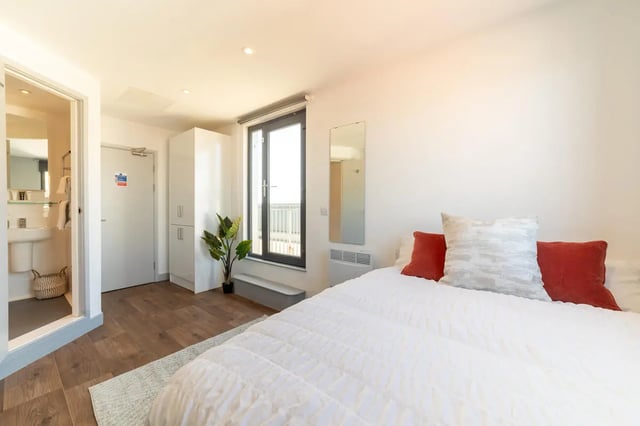 Bed wardrobe plant mirror and bathroom bedroom at The Bridge Phase II in Newcastle Upon Tyne Student Accommodation