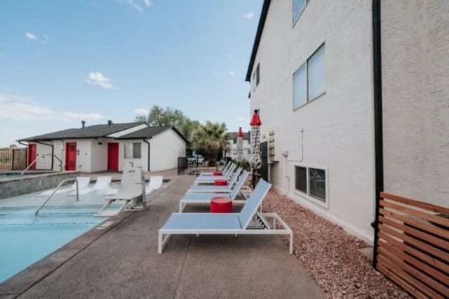 Loungers by pool with building and red doors Exterior at Cedar Flats Student Housing in St. George Student Accommodation