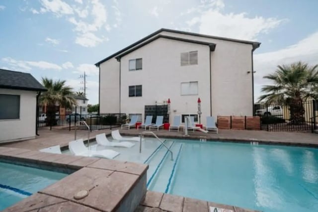 White lounge chairs surround a swimming pool exterior at Cedar Flats Student Housing in St. George Student Accommodation